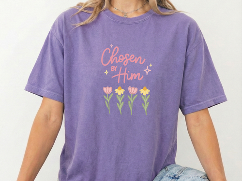 Person wearing a light purple t-shirt with 'Chosen by Him' text and floral design. Sitting in front of a plain background.